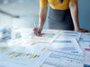 businesswoman standing over a series of paper reports on a desk